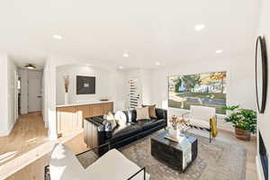 Living room with recessed lighting and light wood flooring