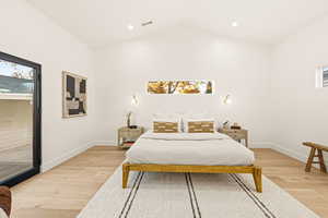 Primary bedroom with access to outside, vaulted ceiling, and recessed lighting