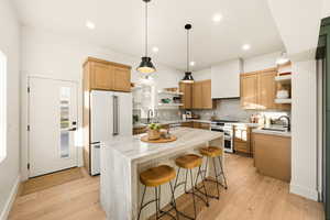 Kitchen featuring open shelves, a kitchen breakfast bar, high appliances, tasteful backsplash, and double oven range