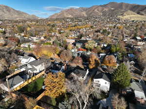 Aerial view of property and surrounding area featuring a mountain backdrop and nearby suburban area