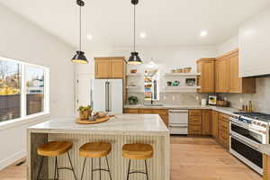 Kitchen featuring a kitchen breakfast bar, GE Cafe appliances, Quartzite counters, decorative backsplash, and recessed lighting