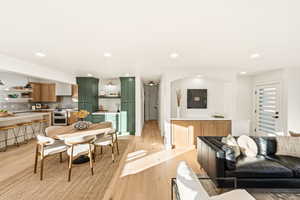 Living room and dining area with light wood flooring and recessed lighting