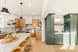 Kitchen with open shelves, green cabinetry, tasteful backsplash, and recessed lighting