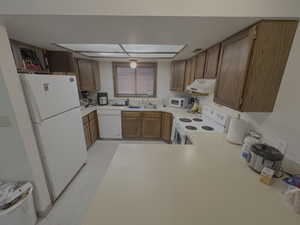 Kitchen featuring white appliances, light countertops, and under cabinet range hood