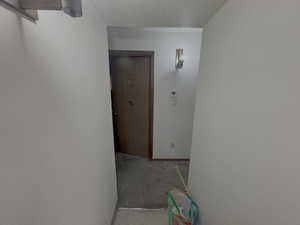 Corridor featuring carpet, a textured ceiling, and a textured wall