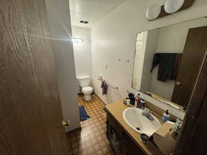Bathroom with a textured ceiling, vanity, a textured wall, and dark flooring