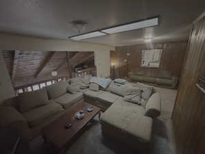 Living area featuring a skylight, wooden walls, a textured ceiling, and beamed ceiling