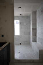 Full bath featuring a tile shower and vanity