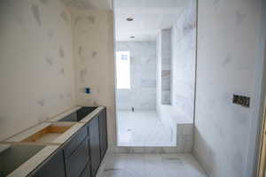 Full bath with walk in shower and light marble finish flooring