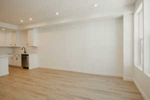 Kitchen with recessed lighting, light wood finished floors, white cabinetry, and stainless steel dishwasher