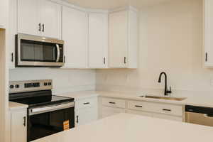 Kitchen featuring appliances with stainless steel finishes, white cabinets, and light stone counters