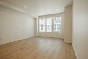 Empty room with light wood finished floors and recessed lighting