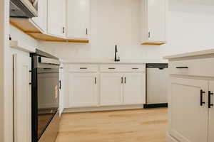 Kitchen with appliances with stainless steel finishes, light countertops, and white cabinetry