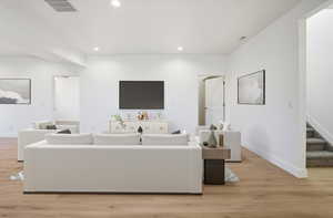 Living room featuring stairs, light wood finished floors, and recessed lighting