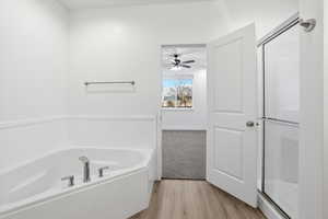 Full bathroom featuring a bath, a shower stall, light wood-style flooring, and a ceiling fan