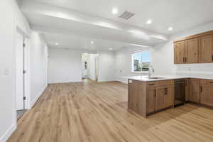 Kitchen featuring a peninsula, light wood-style floors, recessed lighting, open floor plan, and brown cabinets