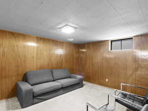 Basement living room featuring light carpet and wooden walls