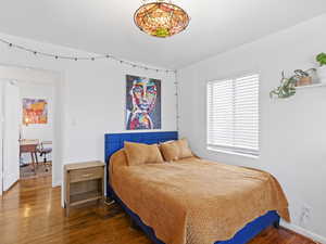 Bedroom with wood finished floors and an office area