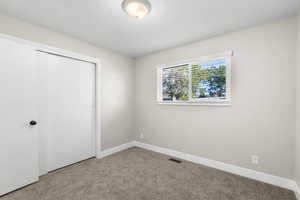 Unfurnished bedroom featuring light colored carpet and a closet
