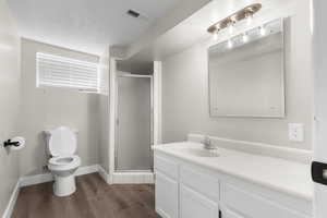 Full bathroom featuring a stall shower, dark wood-style flooring, and vanity