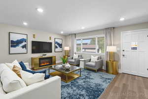 Living area with wood finished floors, recessed lighting, and a glass covered fireplace
