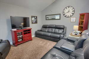 Carpeted living area featuring baseboards and high vaulted ceiling