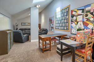 Dining area featuring light carpet, vaulted ceiling, and a skylight
