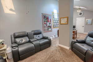 Living room with carpet flooring, ceiling fan, and lofted ceiling
