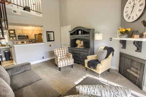 Living room featuring carpet flooring, a fireplace, and a high ceiling