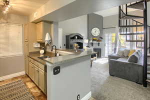 Kitchen featuring open floor plan, a peninsula, dark stone countertops, and light carpet