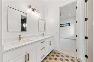 Bathroom with double vanity, recessed lighting, and light carpet