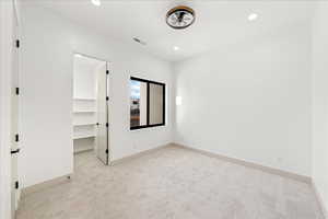 Unfurnished bedroom featuring light carpet, a walk in closet, and recessed lighting