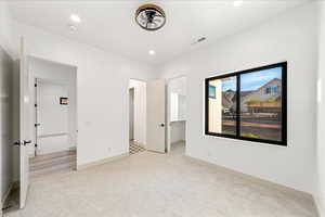 Unfurnished bedroom featuring light carpet, a walk in closet, and recessed lighting