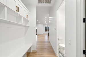 Hallway featuring recessed lighting and light wood-style flooring and convenient half bath.