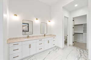 Full bath featuring double vanity, a walk in closet, light marble finish flooring, and recessed lighting