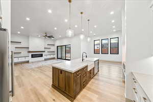 Kitchen featuring open floor plan, light stone counters, a ceiling fan, white cabinetry, and recessed lighting