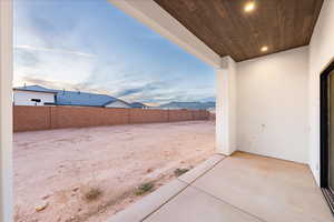 Partially fenced backyard with a patio and a mountain view