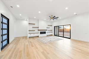 Unfurnished living room with a glass covered fireplace, recessed lighting, light wood-type flooring, and a ceiling fan