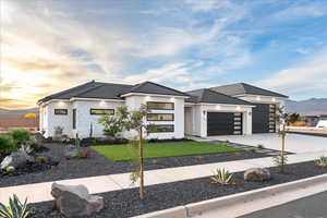 Contemporary home featuring driveway, a garage, a front yard, stucco siding, and a tile roof