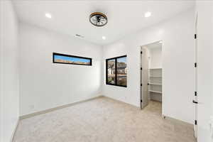 Unfurnished bedroom featuring light colored carpet, a spacious closet, and recessed lighting