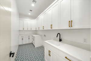 Laundry area with hookup for a washing machine, cabinet space, recessed lighting, and light floors