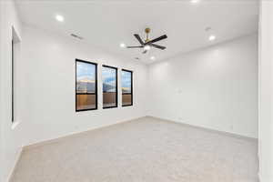 Primary bedroom featuring light carpet, recessed lighting, and a ceiling fan
