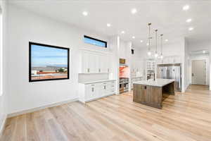 Kitchen with a center island with sink, recessed lighting, white cabinets, pendant lighting, and high quality appliances