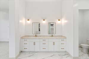 Bathroom featuring double vanity and light marble finish floors