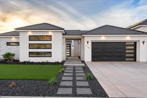 Contemporary home with stucco siding, a garage, stone siding, and driveway