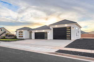 Modern home featuring a garage, concrete driveway, stucco siding, and a tile roof