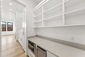Bar featuring recessed lighting, light wood-style flooring, white cabinetry, light stone counters, including a wine fridge and oven