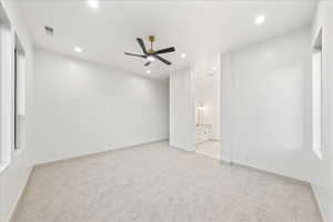 Primary bedroom with light carpet, a ceiling fan, recessed lighting, and connected bathroom