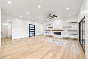 Unfurnished living room featuring recessed lighting, light wood-style flooring, ceiling fan, and a glass covered fireplace