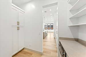 Butler pantry with light wood-style floors and recessed lighting